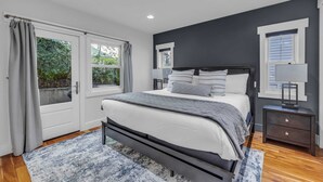 Een moderne slaapkamer met een groot bed, een nachtkastje en een raam met gordijnen.