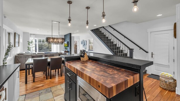Een moderne keuken met een houten eiland, zwarte aanrechtbladen en hangende吊灯.