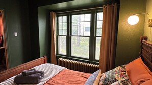 Une pièce avec un lit, une fenêtre, un radiateur et une lampe.