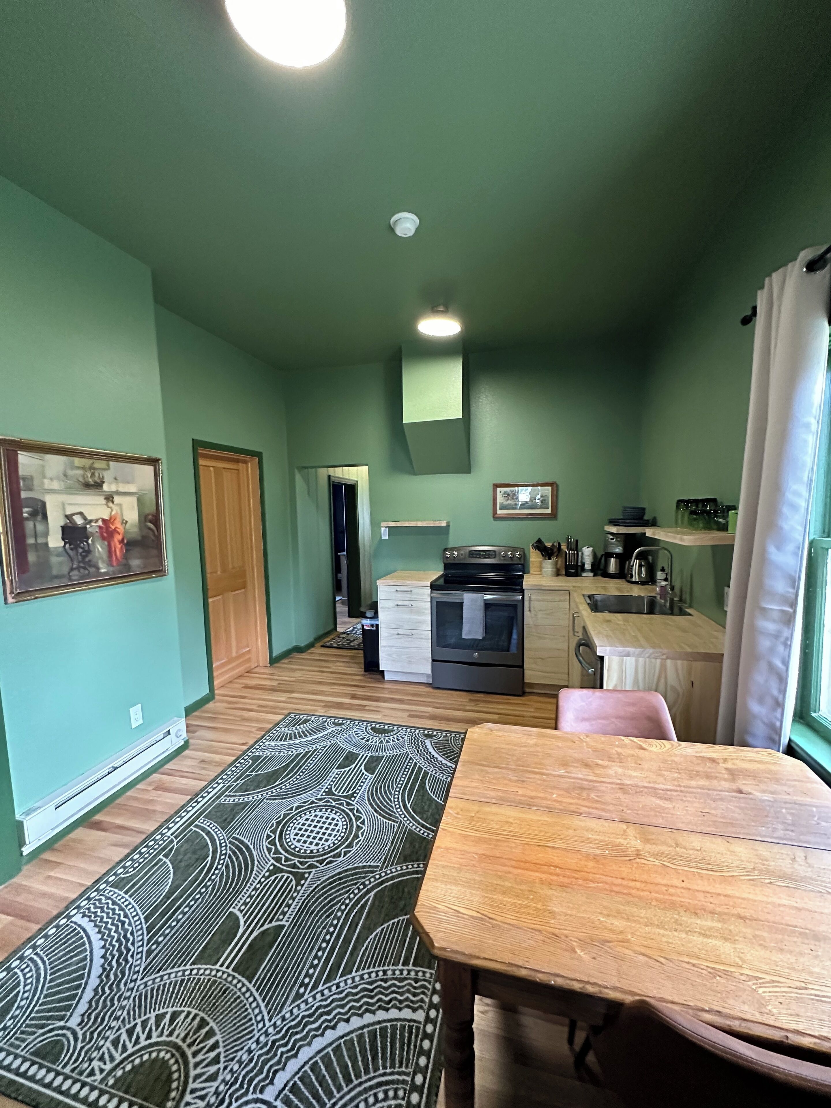 A compact living space with a dining area, kitchenette, and a hallway leading to another room.