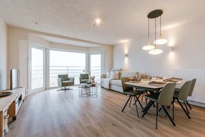 Enjoy meals with family and friends at the dining table, surrounded by a comfortable seating area with a sofa and armchairs.