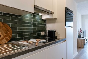 Enjoy cooking in this well-lit kitchen with sleek cabinetry, a black countertop, and a green-tiled backsplash.