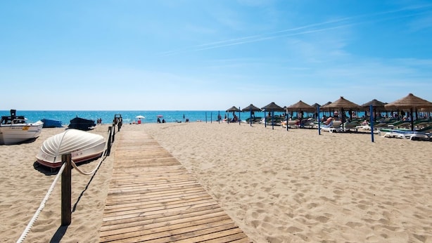 A wooden boardwalk leading to beach umbrellas and lounge chairs. - Cozy Apartment on the Beach, ideal for couples (FUENGIROLA)
