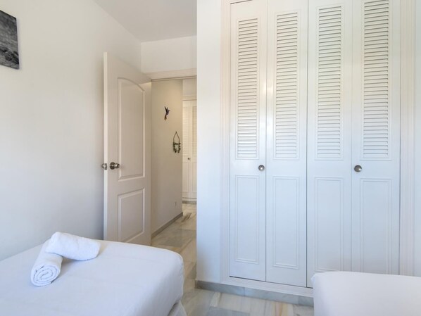 Ein Hotelzimmer mit Bett, Badezimmer mit Dusche und Schrank mit Schlaufenklappen.
