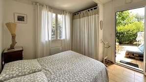 A bedroom with a bed, a window with curtains, a radiator, and a view of the outside. - Apartment for 4 guests, pet-friendly, 5 minutes from Almanarre Beach – Hyères (HYERES)