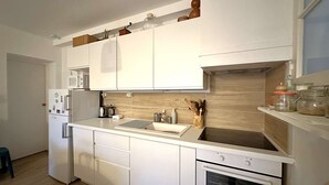 A modern kitchen with white cabinets, a built-in microwave, a stainless steel sink, and a stove. - Apartment for 4 guests, pet-friendly, 5 minutes from Almanarre Beach – Hyères (HYERES)