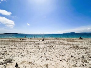 A beach with clear blue water and distant mountains.