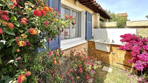 A rustic house with a wooden exterior, a window with blue shutters, and a white outdoor sink. - Apartment for 4 guests, pet-friendly, 5 minutes from Almanarre Beach – Hyères (HYERES)