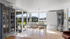 Une pièce spacieuse avec un plancher en bois, une table à manger avec des chaises et une vue sur l’extérieur.