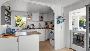 Une cuisine moderne avec des meubles blancs, un plan de travail en bois et de la vaisselle bleue.