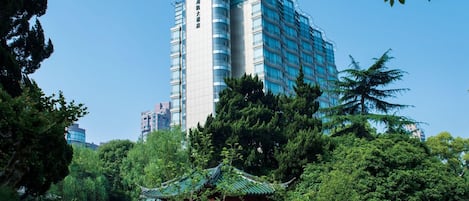 A modern hotel with a traditional pavilion by a pond.
