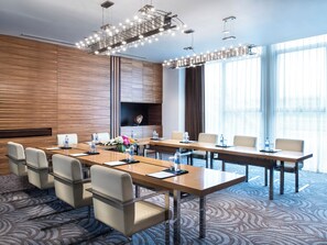 A conference room with a long table, chairs, a flat-screen TV, and a decorative light fixture. - Grand Millennium Shanghai Hongqiao (Shanghai)