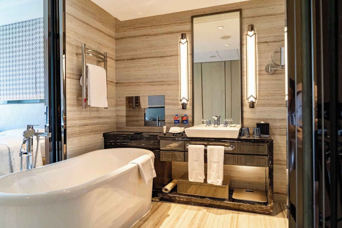 Une salle de bain moderne avec une baignoire sur pieds, un grand miroir et un meuble-lavabo doté d’un évier et d’un porte-serviettes.