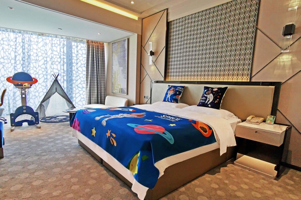 Una habitación de hotel con una cama grande, un escritorio, una silla, una mesita y una estructura parecida a una tienda de campaña.
