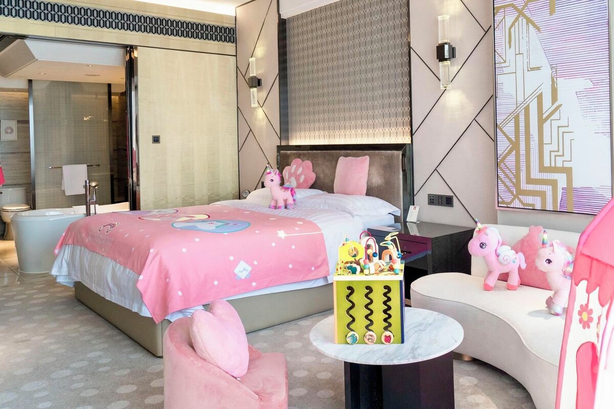 Una habitación de hotel moderna con una cama grande, una zona de estar y un baño.