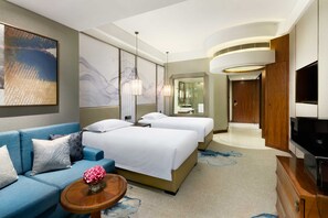 A hotel room with a bed, a sofa, a TV, and a bathroom visible through a glass door. - Grand Millennium Shanghai Hongqiao (Shanghai)