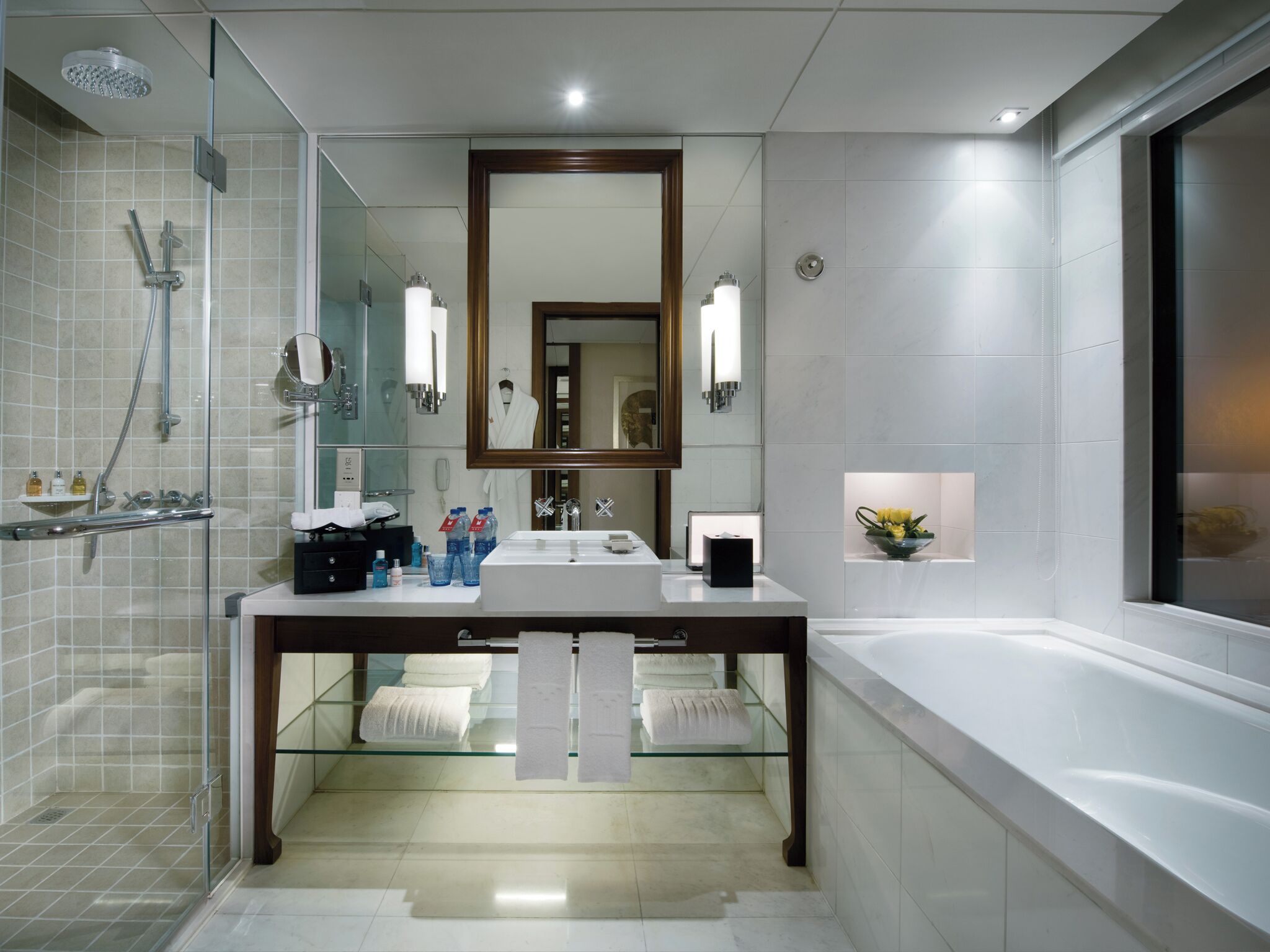 A modern bathroom with a glass shower enclosure, a large mirror, a vanity with a sink, and a bathtub.