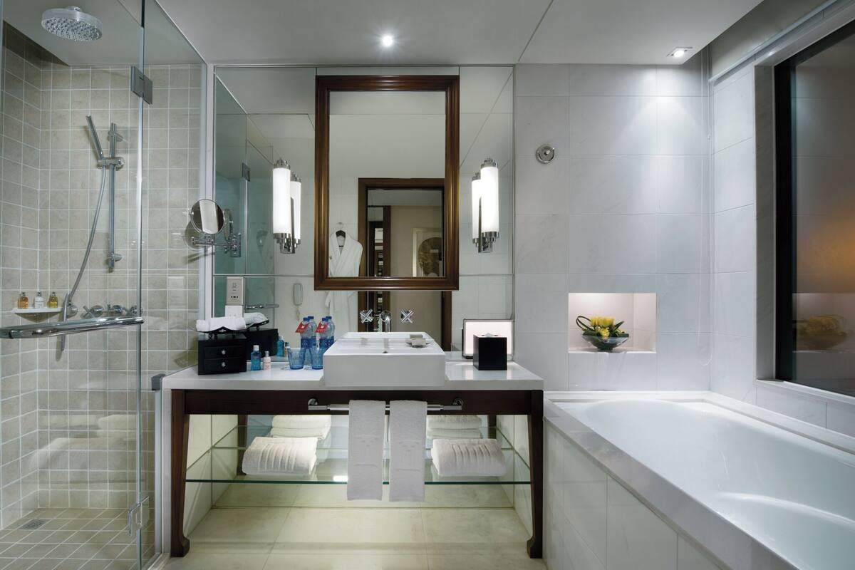 Une salle de bain moderne avec une douche à parois de verre, un grand miroir et une baignoire.