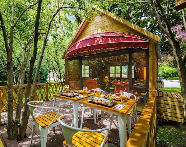A wooden gazebo with a red awning, surrounded by trees, featuring outdoor seating with tables and chairs. - Grand Millennium Shanghai Hongqiao (Shanghai)