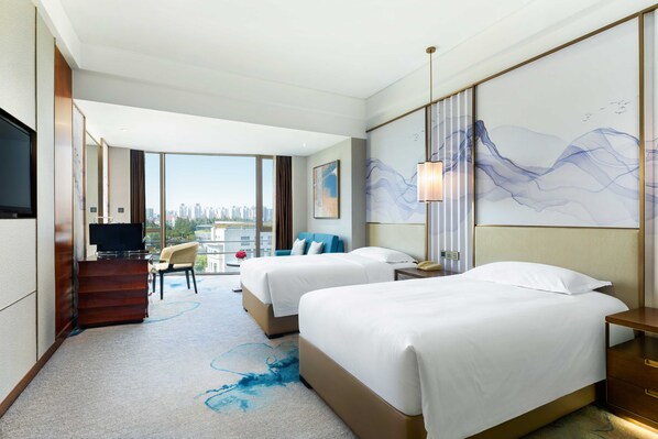 A hotel room with two beds, a TV, a desk, and a large window with a city view. - Grand Millennium Shanghai Hongqiao (Shanghai)