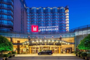A hotel with a modern facade, a prominent entrance, and a car parked in front.