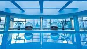 Ein moderner, überdachter Pool mit großen, hängenden Sesseln und Blick auf die Stadt.