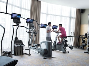 A gym with stationary bikes, treadmills, and weight machines, with large windows and curtains. - Grand Millennium Shanghai Hongqiao (Shanghai)