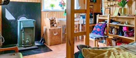 Una habitación acogedora con cama, una silla de madera, una mesita y un estante con diversos objetos.