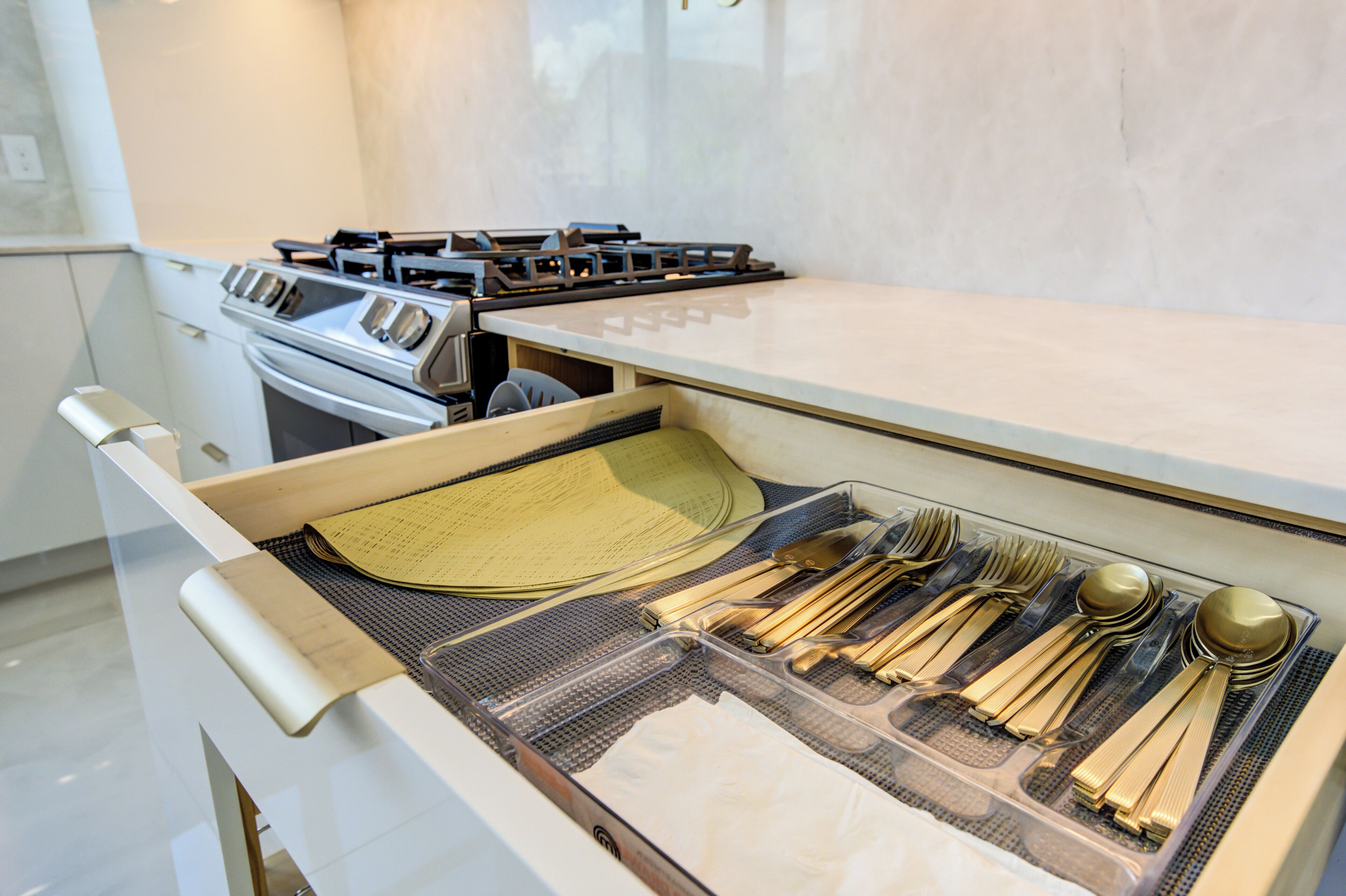 Een keuken met een fornuis, oven en een lade met keukengerei.