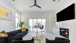 Un salon moderne avec un canapé noir, une table basse en verre et un téléviseur à écran plat fixé au mur.