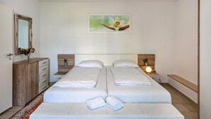 A hotel room with two beds, a wooden dresser, a mirror, a painting, and a bedside lamp. - Aldars Urban Trio Suites No. 2 with Balcony, Wi-Fi and Air Conditioning (München)