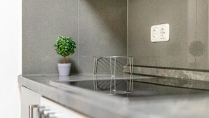 A kitchen with a modern design, featuring a stainless steel countertop, a potted plant, and a power outlet on the wall. - Aldars Urban Trio Suites No. 2 with Balcony, Wi-Fi and Air Conditioning (München)