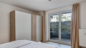 A bedroom with a bed, a sliding glass door to a balcony, and a white radiator. - Aldars Urban Trio Suites No. 2 with Balcony, Wi-Fi and Air Conditioning (München)