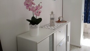 A white console table with a potted orchid, a glass lantern, and a small sculpture.