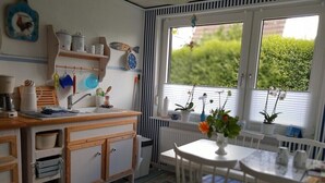 A compact kitchen with wooden cabinets, a sink, and a window with a view of greenery.