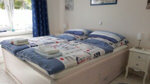 A bed with a quilt, pillows, a bedside table, and a rug with an anchor design.