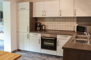 Eine moderne Küche mit hellen Schränken, einem Backofen, einer Mikrowelle und einem Spülbecken.