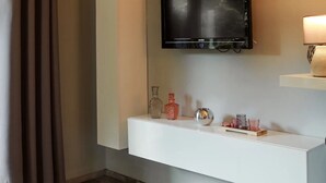 Une salle de bain moderne équipée d’un téléviseur fixé au mur, d’un meuble-lavabo avec miroir et d’une étagère agrémentée d’objets décoratifs.