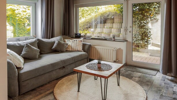 Un salon avec un canapé, une table basse, un radiateur et une vue sur la verdure à l’extérieur.