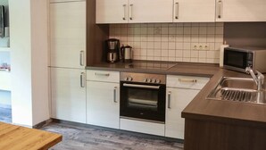 Une cuisine moderne avec des meubles blancs, un four encastré, un four à micro-ondes et une machine à café.