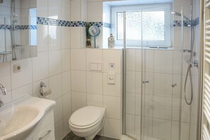 A bathroom with a toilet, sink, shower, and a window. - Apartment 'Fewo Malerstübchen' with Private Terrace and Wi-Fi (Willingen (Upland))