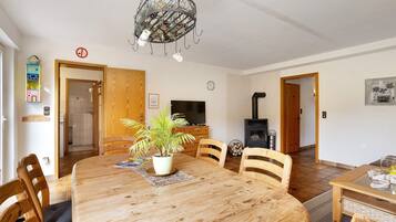 A dining area with a wooden table, chairs, a potted plant, a television, and a fireplace.