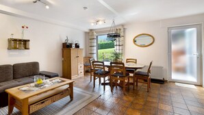 Een woonkamer met een bank, een eettafel, stoelen en een salontafel.