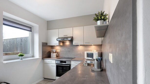 Cocina compacta con una isla grande, horno integrado y ventana con vistas.