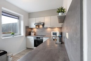 Cocina compacta con una isla grande, horno integrado y ventana con vistas.