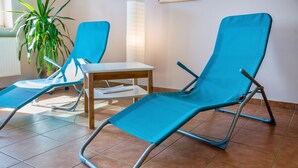 Una habitación con dos sillones azules, una mesa de madera y una planta en maceta.