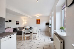 Una cocina moderna con comedor, electrodomésticos blancos y vistas al atardecer.