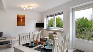 Un comedor con una mesa lista para el desayuno, un televisor en la pared y una ventana con vistas a zonas verdes.