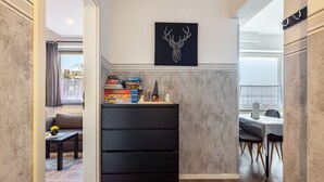 Un intérieur moderne avec un meuble de rangement noir, une décoration murale représentant une tête de cerf et un coin repas comprenant une table et des chaises.