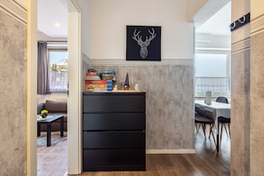 Et moderne interiør med en sort opbevaringsenhed, et vægmonteret billede af et dådyr og et spiseområde med bord og stole.